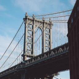 Manhattan Bridge tower and cables against blue sky, iconic New York landmark for Miami to NYC route