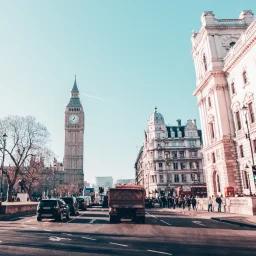 Big Ben clock tower and historic London architecture viewed from busy street with classic cars
