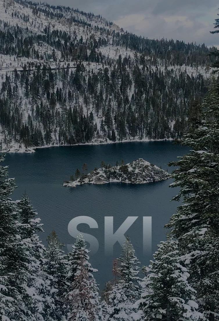 Snow-covered alpine lake surrounded by evergreen forests and mountain peaks in Lake Tahoe winter landscape