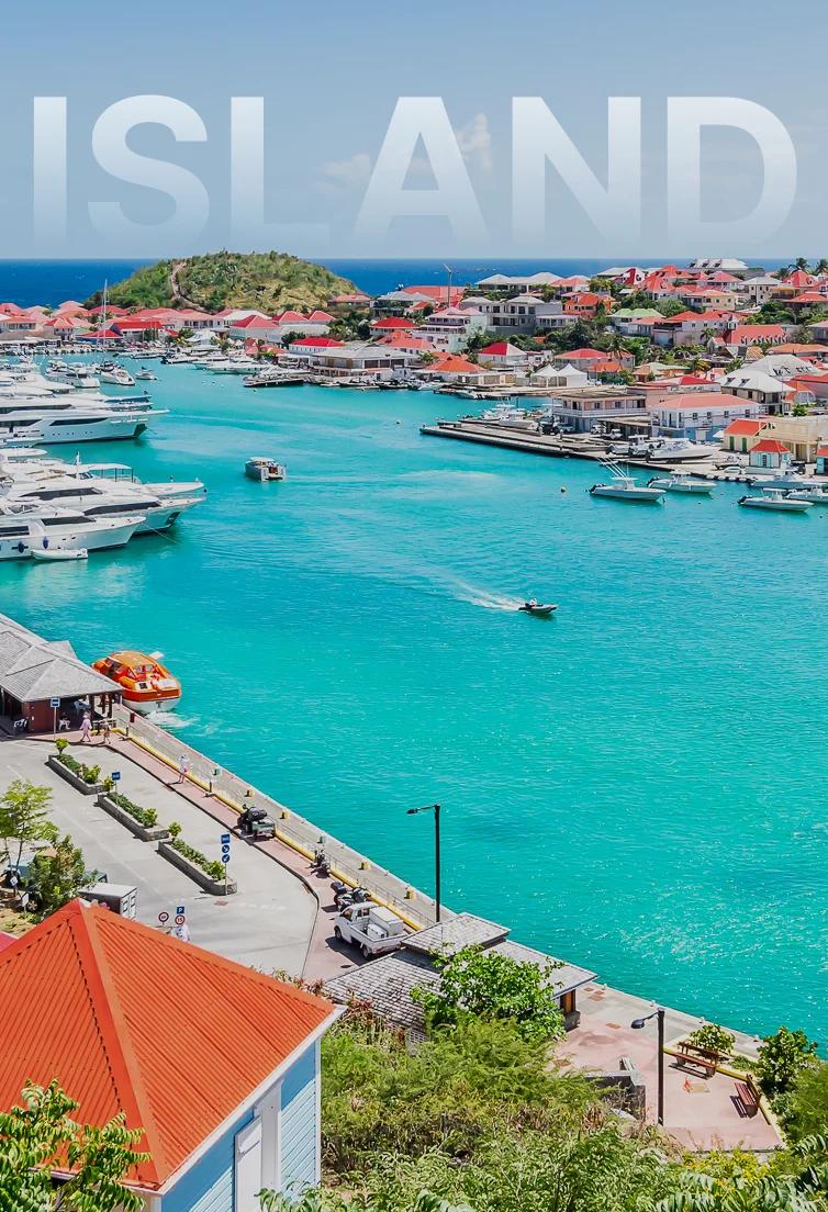 Aerial view of Gustavia harbor in St. Barts with turquoise waters, luxury yachts, and red-roofed buildings