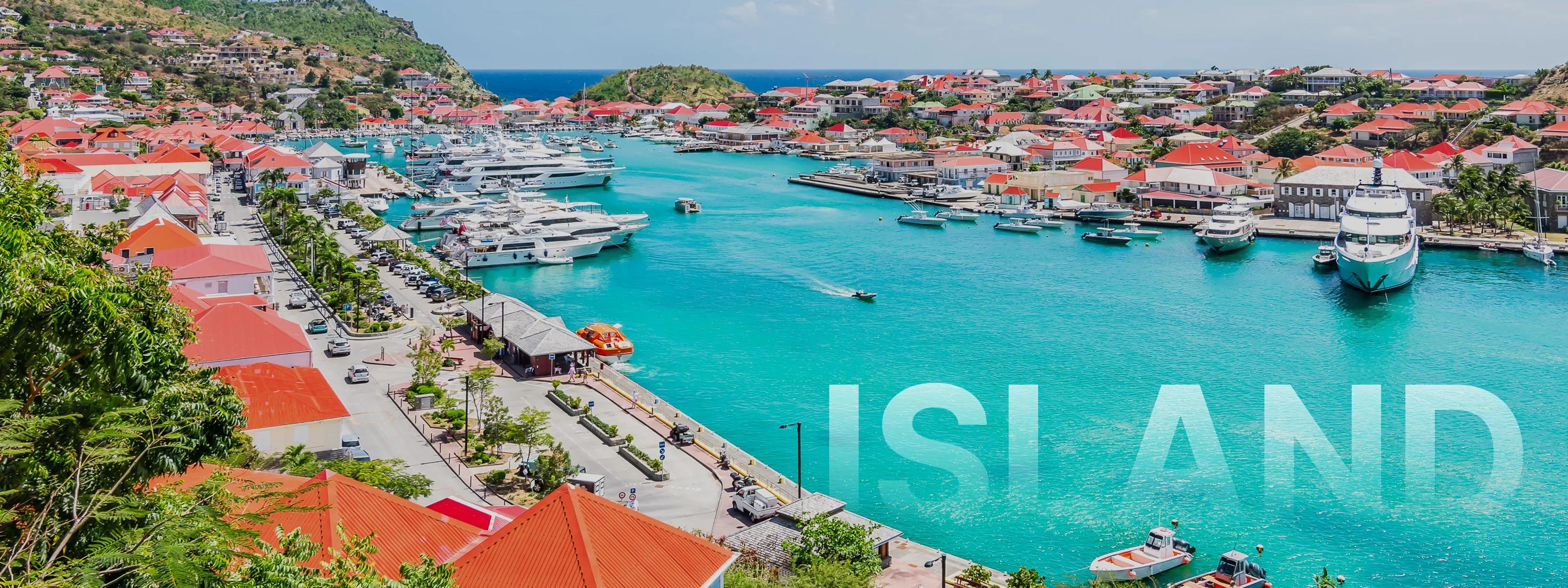 Aerial view of Gustavia harbor in St. Barts with turquoise waters, luxury yachts, and red-roofed buildings