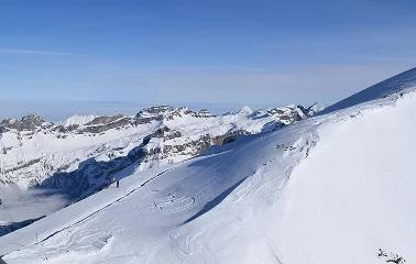 Snow-covered ski slopes and mountain peaks at Jackson Hole resort under clear blue winter sky