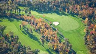 Aerial view of pristine golf course fairways winding through vibrant autumn foliage in Monterey