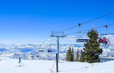 Ski lift carrying passengers up snowy mountain slopes with panoramic alpine views at Jackson Hole