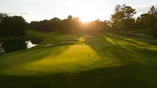 Pristine golf course green with flag at sunset, surrounded by lush fairways and trees in Palm Beach