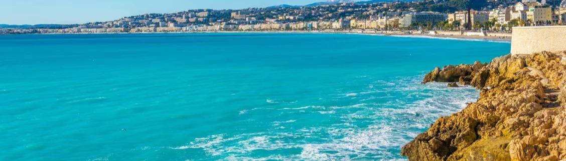 Stunning turquoise Mediterranean coastline of Nice with golden cliffs and elegant French Riviera cityscape
