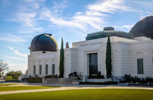 Griffith Observatory's iconic white Art Deco building with copper domes against blue sky in Los Angeles
