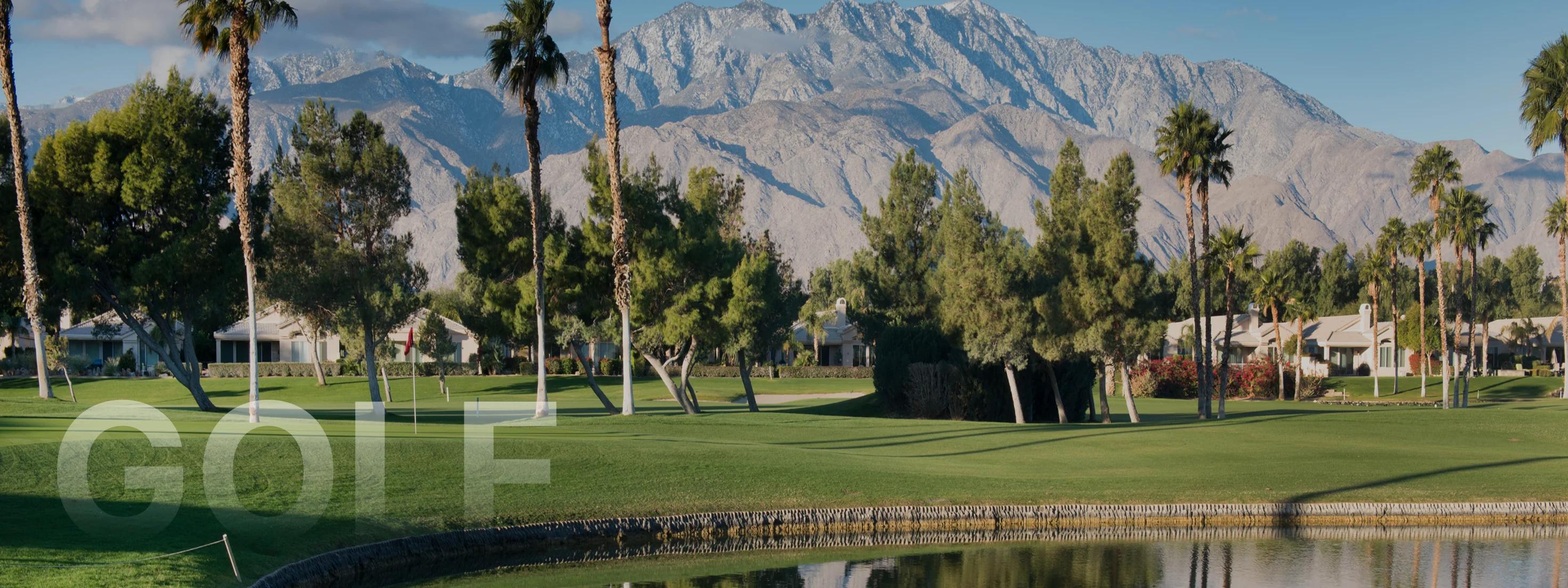 Pristine golf course with manicured greens and palm trees against dramatic snow-capped mountains in Palm Springs