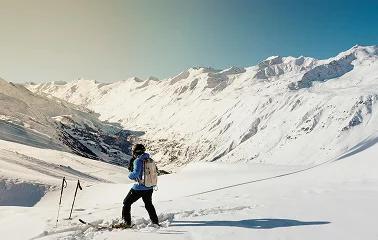 Skier descending pristine powder slopes surrounded by snow-covered mountain peaks in alpine terrain