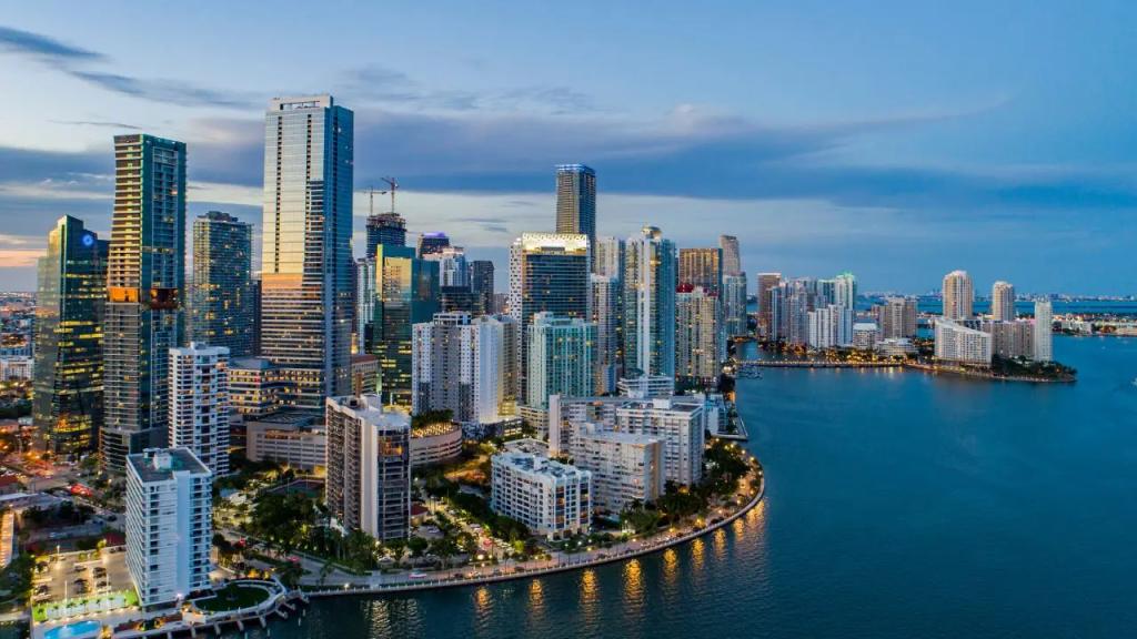Miami skyline at dusk with illuminated skyscrapers and waterfront, showcasing a premier destination for private jet travel
