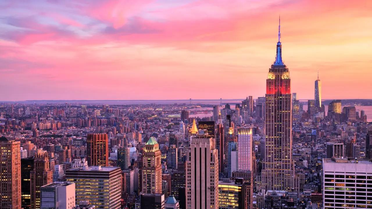 Manhattan skyline at sunset with Empire State Building illuminated, showcasing luxury travel destination