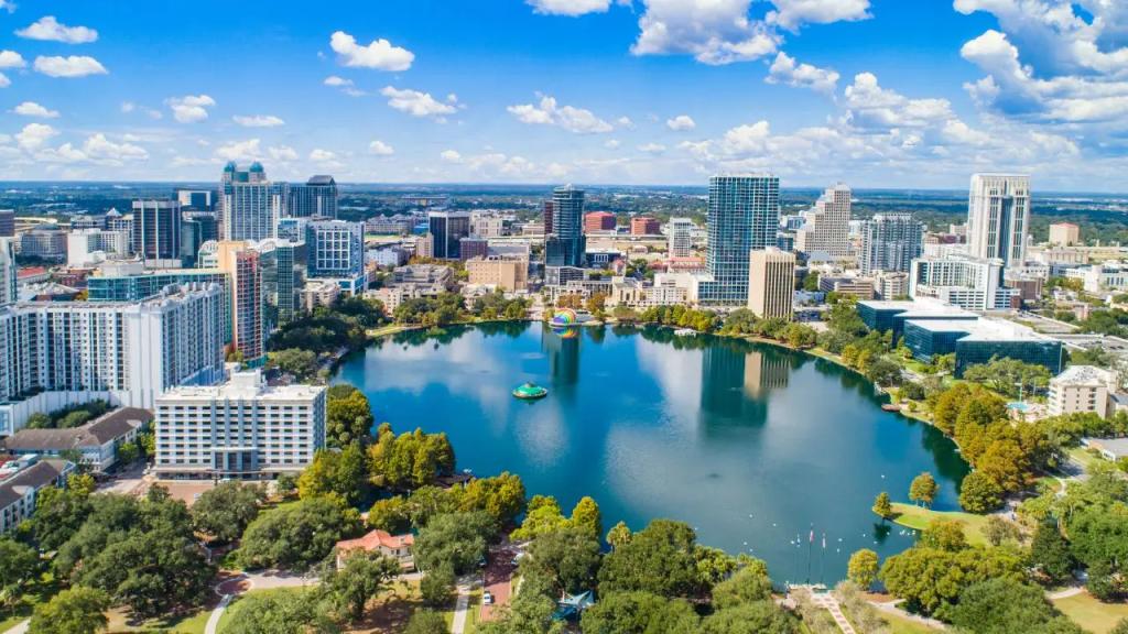 Aerial view of Orlando downtown skyline with Lake Eola reflecting modern skyscrapers under blue sky