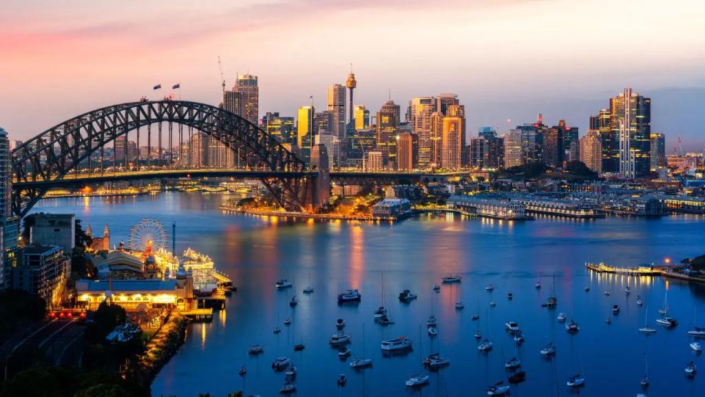 Sydney Harbor Bridge and illuminated city skyline at dusk with luxury yachts anchored in the harbor